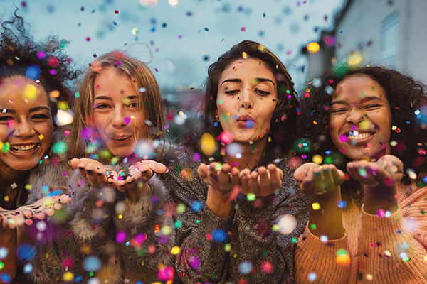 Young women blowing confetti from hands