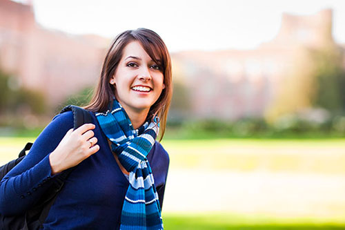 Smiling female college student holding a backpack