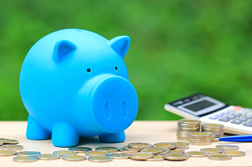 Stack of coins and a blue piggy bank