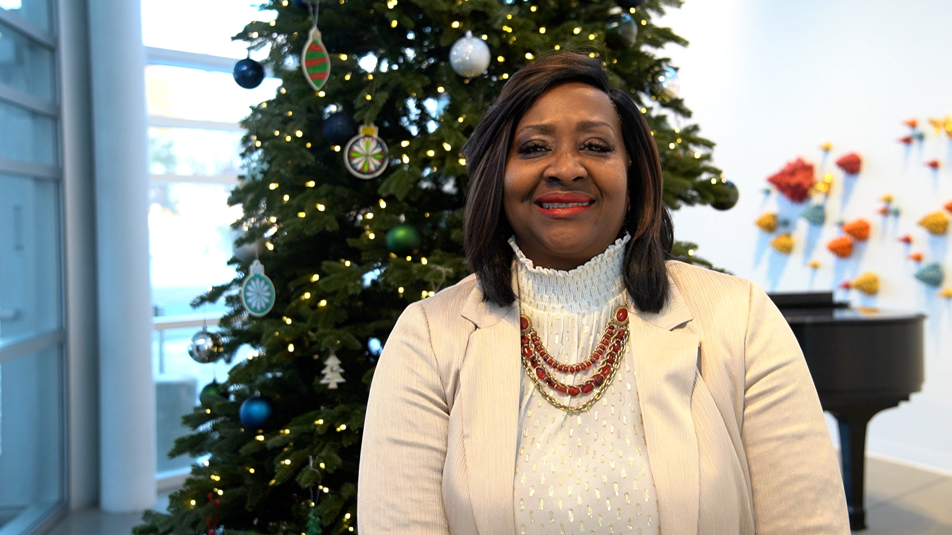 Bay College President Dr. Nerita Hughes speaking in front of the Christmas tree in the Escanaba campus Besse Center.