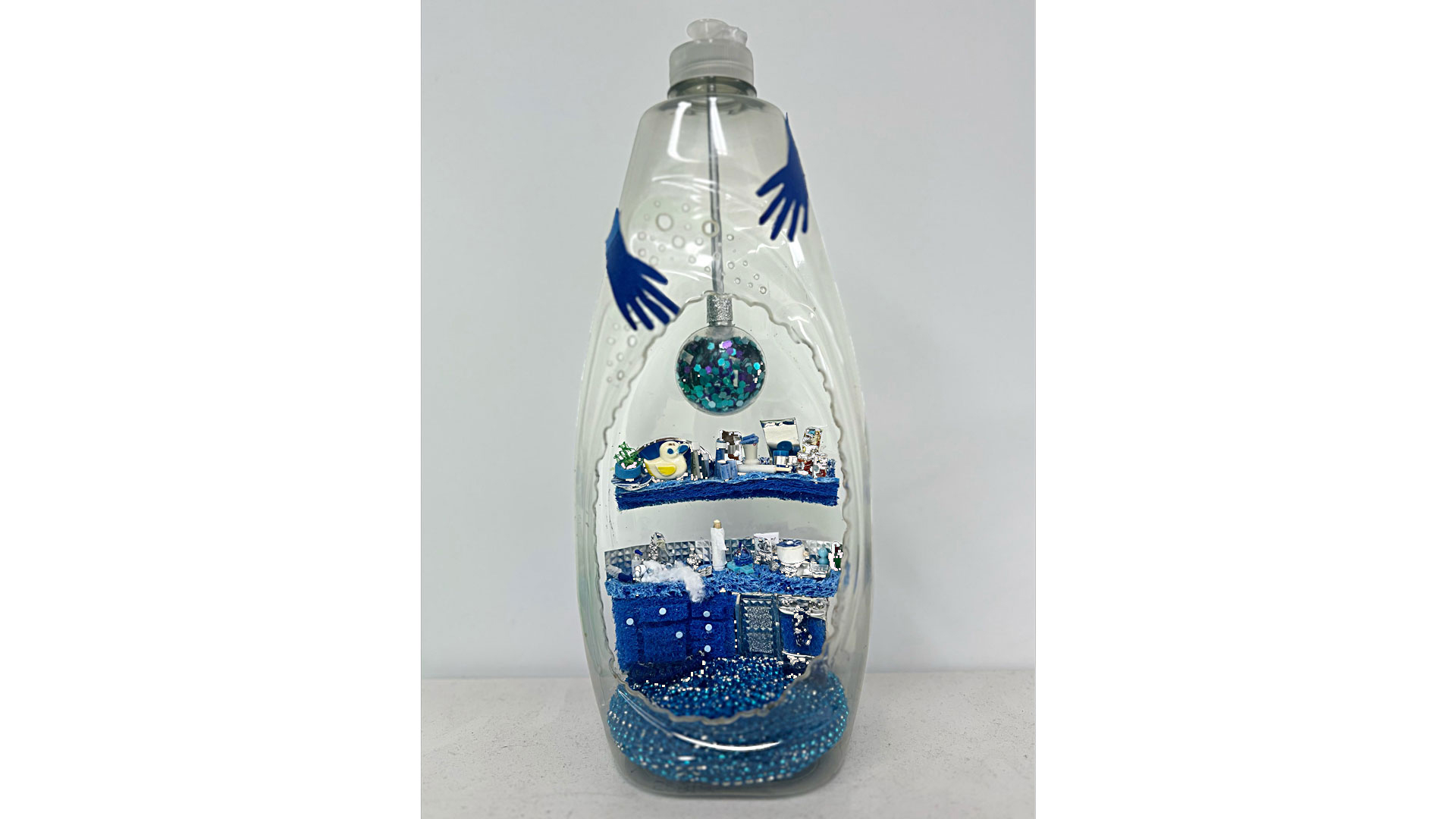Clear dish soap bottle with a microcosm of tiny objects inside of it, decoarated like a tiny house.