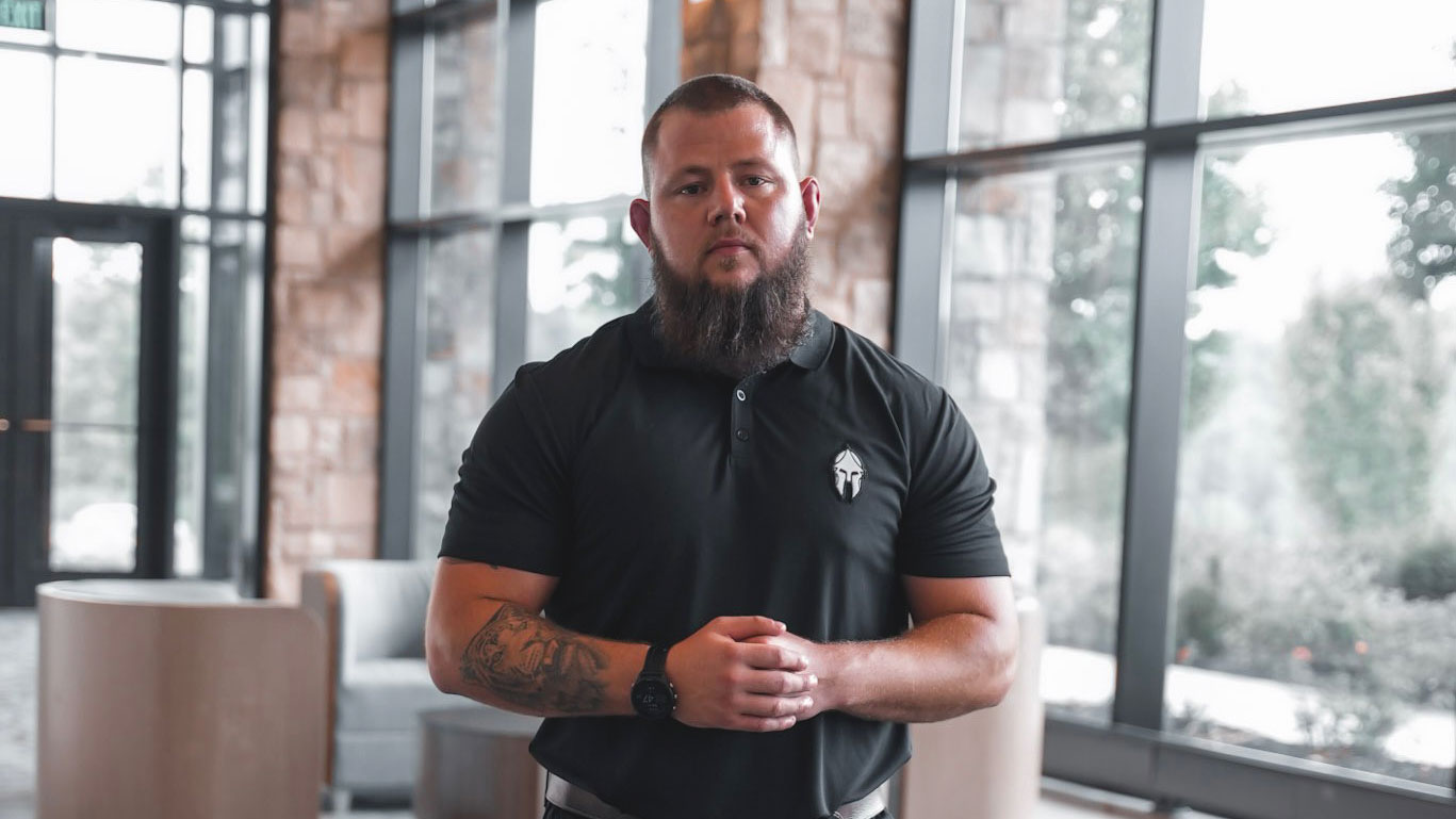 Motivational Speaker Seth Gehle standing in the light of a wall of windows in a huge room that looks like a college campus lobby.